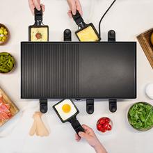 Cheese&Grill 12000 Inox Black. ‌Raclette de queijo e grill de 2000 W, grelha superior mista, acabamentos em aço inoxidável, placa antiaderente, 8 frigideiras individuais, design amovível