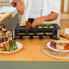 Appareil à raclette Cheese&Grill 16000 Inox Noir pour 8 personnes avec un grill de 1400 W. Avec une structure design avec des finitions en acier inoxydable, un thermostat réglable et une plaque de cuisson antiadhésive en fonte d'aluminium avec une surface mixte grill-fer. Comprend 8 petites poêles antiadhésives et 8 spatules en bois.