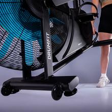 Drumfit WOD Rider Ultimate bicicleta de aire de alto rendimiento con ventilador de 679,5 mm que ofrece resistencia progresiva, pedaleo bidireccional, doble correa suave y silenciosa, pantalla LCD y conectividad.  Rendimiento para usuarios de hasta 150 kg con y ruedas de transporte.