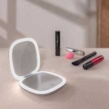 Mini Espelho FaceCare. Espelho de maquiagem dupla face com aumento de 10x e um espelho com aumento de 1x, ambos com iluminação LED. Possui sensor de toque, brilho ajustável e três temperaturas de luz (fria, quente e natural). Alimentado por uma bateria recarregável de 600 mAh e carregamento USB-C.